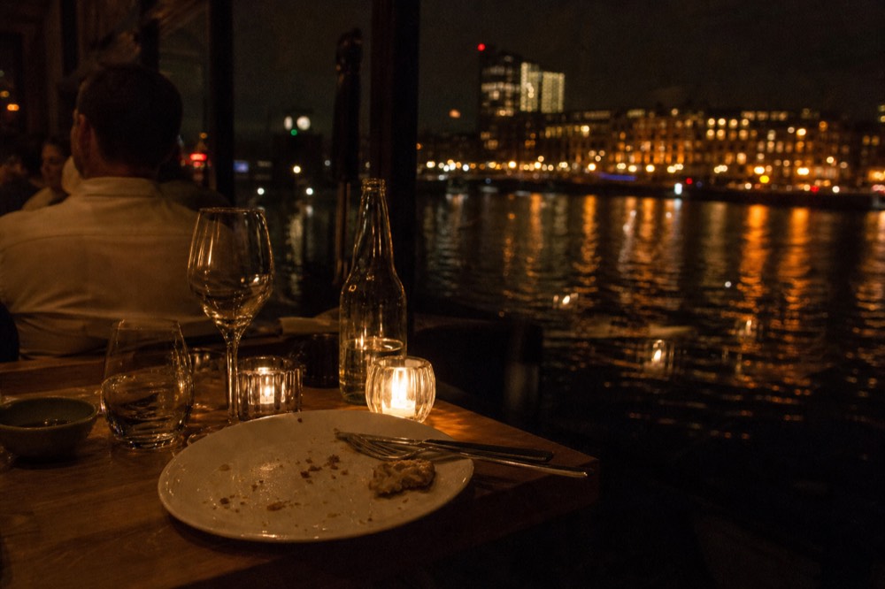 Candlelit table setting on a dinner cruise with Budapest lights reflected on the Danube, no text, no logos, no people