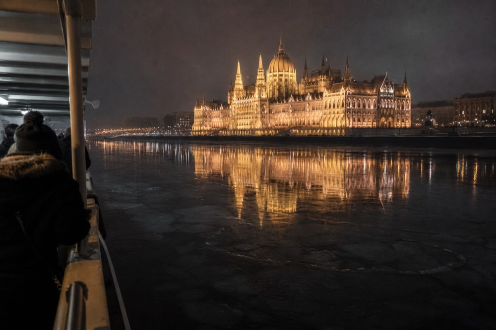 Illuminated Hungarian Parliament Building reflected in the Danube at night from a cruise boat, no text, no logos, no people