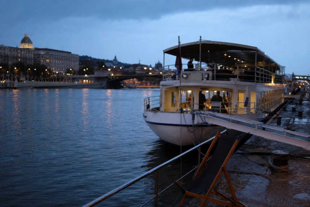 A river cruise boat moored on the Danube embankment at dusk, no text, no logos, no people.