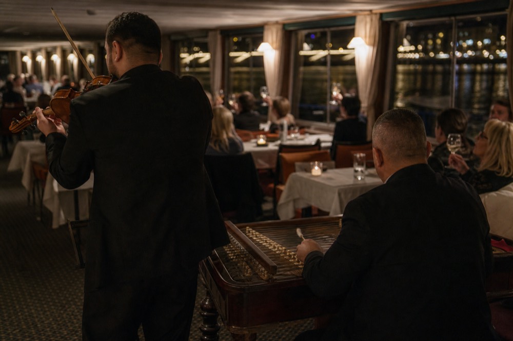 Musicians performing inside a river cruise cabin during a dinner sailing, no text, no logos, no people.