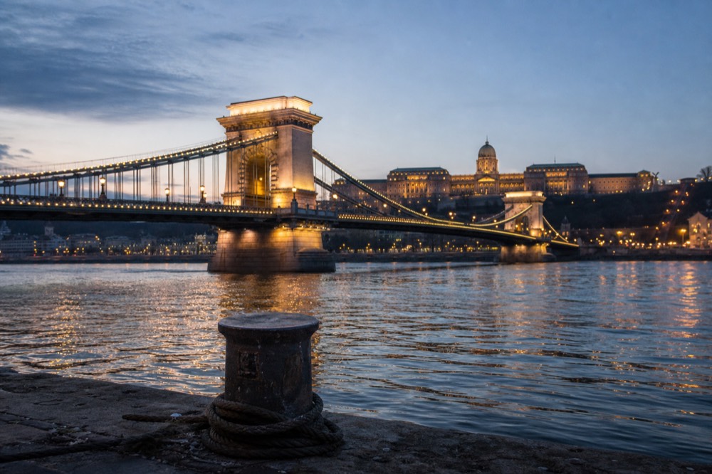 Evening view of the illuminated Chain Bridge and Buda Castle from the Danube, no text, no logos, no people.