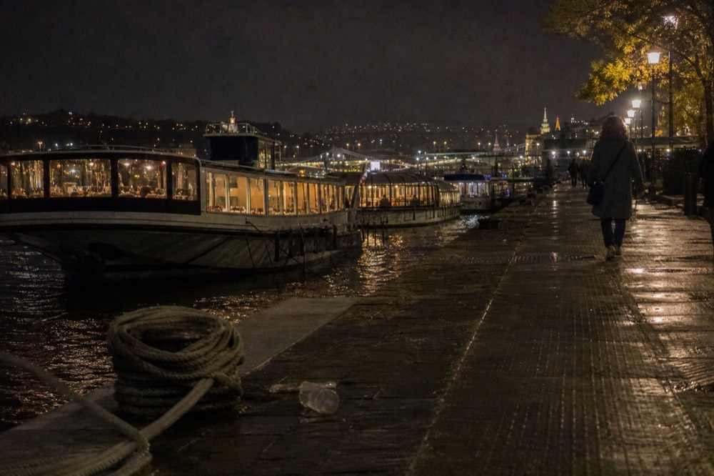 A river cruise dock on the Pest embankment with boats moored at night, no text, no logos, no people.