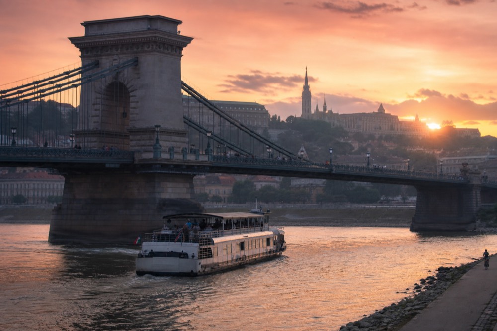 Sunset over the Danube with a cruise boat passing under the Chain Bridge, no text, no logos, no people