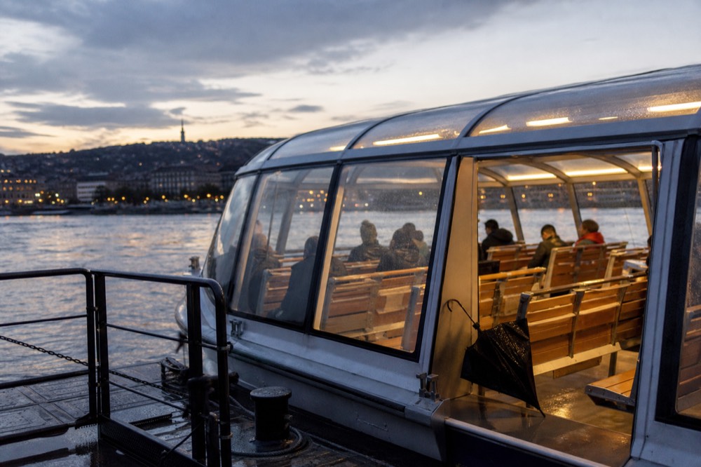 Glass-enclosed panoramic cruise boat on the Danube in Budapest at dusk, no text, no logos, no people