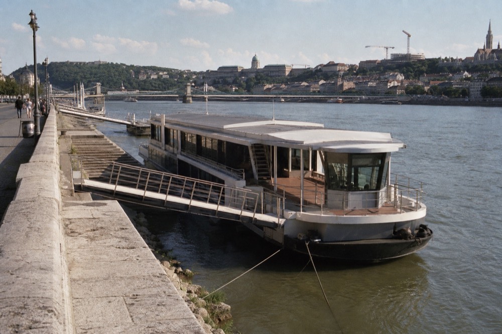 Numbered boarding dock and gangway on the Pest embankment beside moored sightseeing boats, no text, no logos, no people
