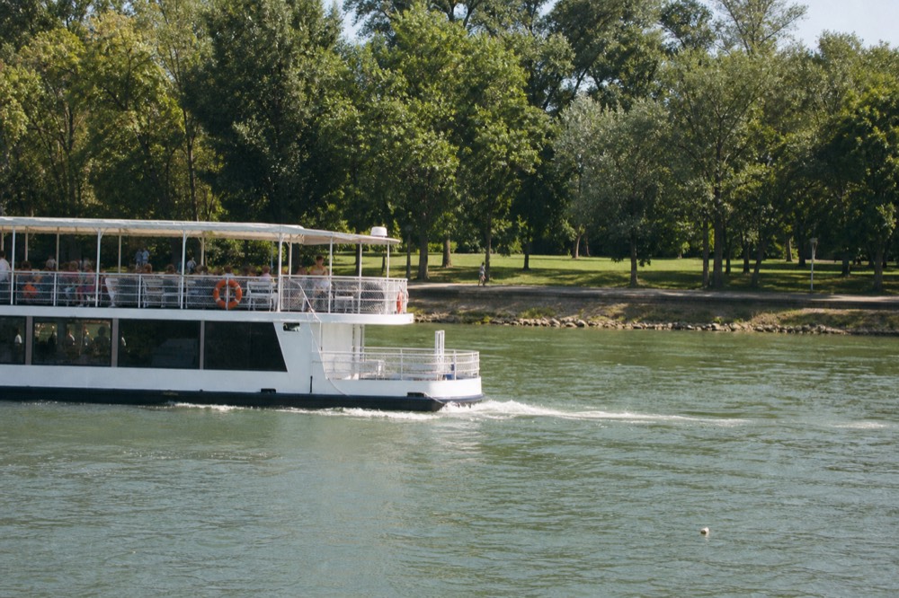 A daytime cruise boat passing Margaret Island on the Danube, no text, no logos, no people