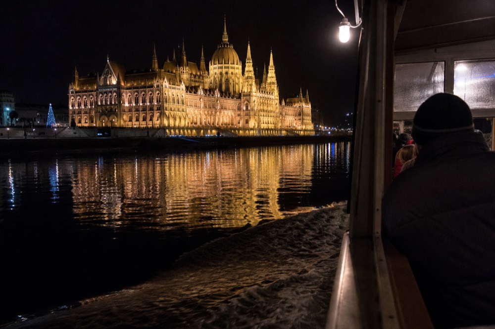 Illuminated Hungarian Parliament Building reflected in the Danube at night from a cruise boat, no text, no logos, no people